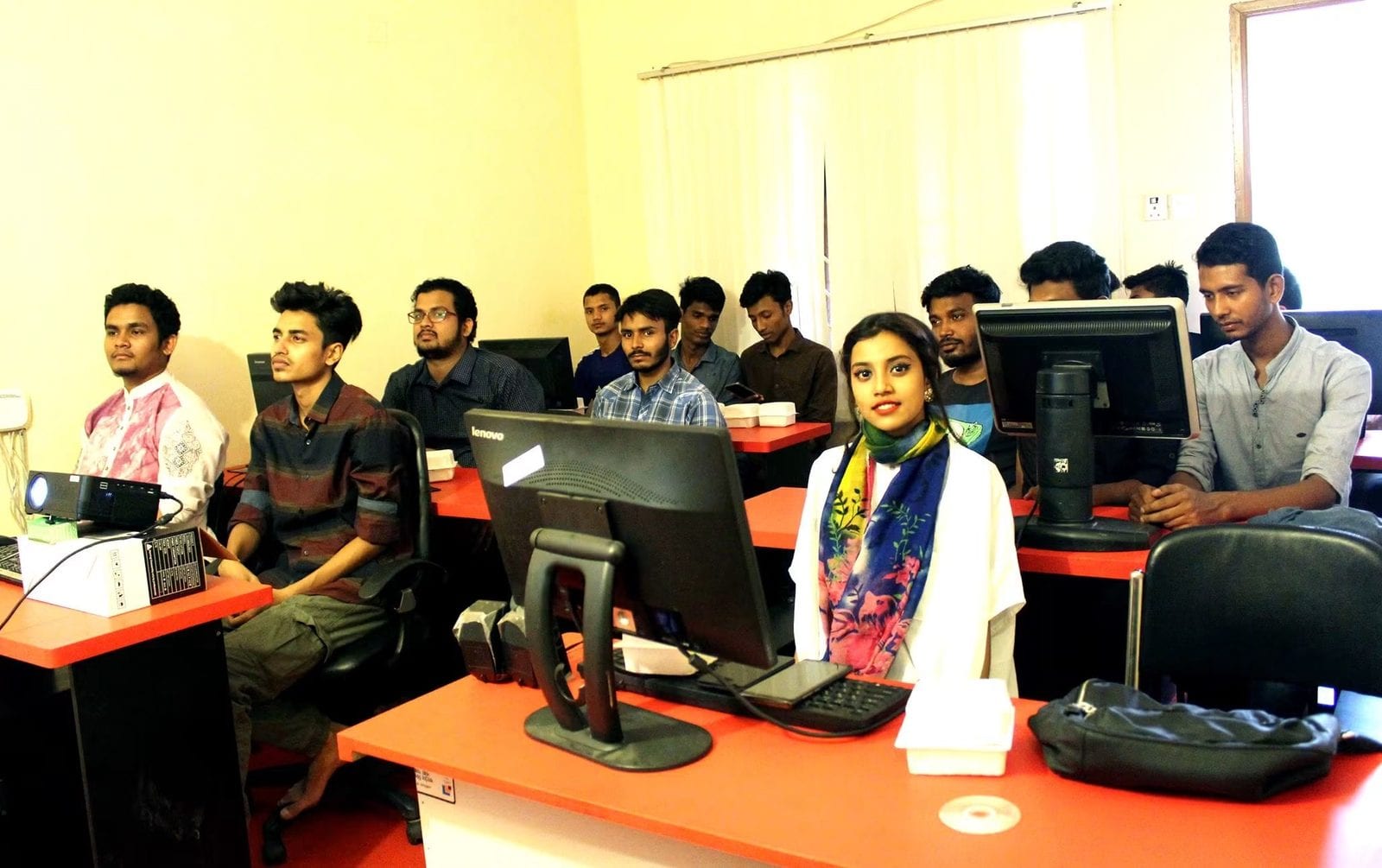 A wide view of students at workstations in the training room.