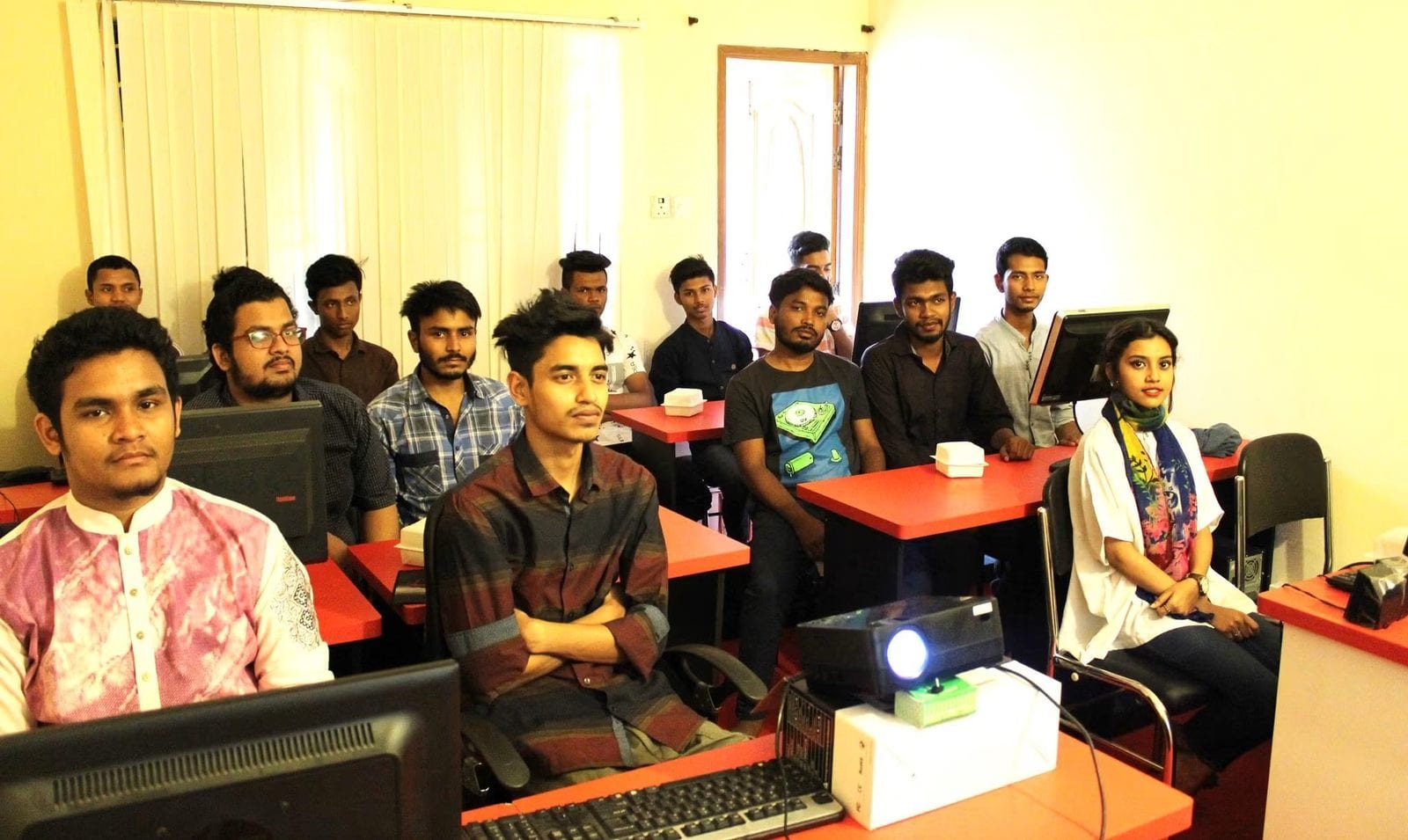 Students seated at computer workstations in a classroom.